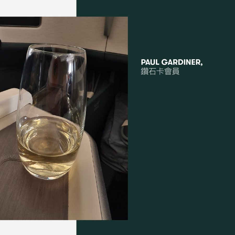 A glass of champagne on a tray table on a Cathay Pacific aircraft.